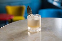 a glass with ice and a feather on the edge sitting on a table in a restaurant