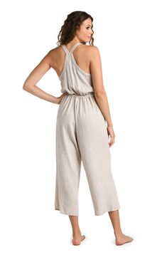 Effortlessly chic, this taupe-colored cover-up complements any beach ensemble, offering a versatile and neutral layer for your seaside adventures. This jumpsuit features a cropped, wide-leg design, with adjustable shoulder straps and a drawstring waist for a customizable fit. The back showcases a cross-strap detail, adding a touch of elegance to the relaxed fit, making it both functional and fashionable for summer days. [split] Details Jumpsuit cover up Cropped length Drawstring waistband Pocket Beige Linen Summer Jumpsuits And Rompers, Summer Beach Jumpsuits And Rompers With Elastic Waistband, Beach Jumpsuits And Rompers With Adjustable Straps, Chic Jumpsuits And Rompers With Adjustable Straps For Vacation, Casual Beige Jumpsuits And Rompers For Vacation, Casual Beige Jumpsuit For Vacation, Linen Jumpsuit For The Beach, Summer Beach Jumpsuit With Elastic Waistband, Chic Beach Jumpsuits And Rompers With Adjustable Straps