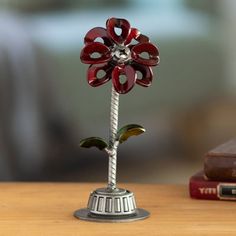 a small metal flower on top of a wooden table next to a bookshelf