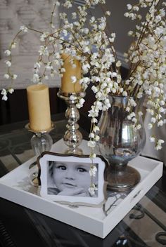 a glass table topped with a vase filled with white flowers and a small photo frame