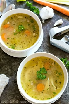 two bowls of soup with carrots, celery and parsley on the side