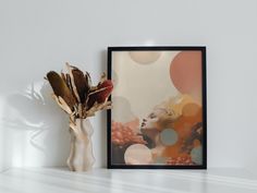 a vase with dried flowers in it next to a framed photograph on a white shelf