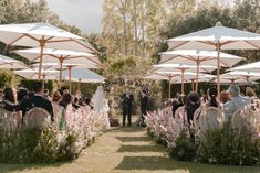 an outdoor wedding ceremony with umbrellas and flowers