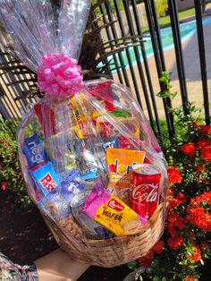 a basket filled with candy and snacks sitting on top of a bench next to flowers