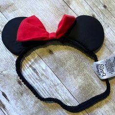 a mickey mouse ears headband with a red bow on the side and a tag attached to it