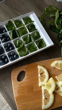 sliced up lemons and blueberries on a cutting board next to an ice tray