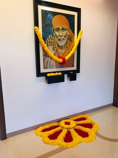 a painting on the wall next to a yellow flower arrangement in front of a framed photo