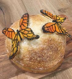 three monarch butterflies on top of a piece of bread that is sitting on a wooden table