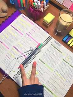 a person's hand is pointing at a menu on a desk with markers and crayons