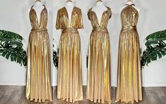 three gold dresses on mannequins in front of a plant