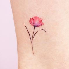 a small pink flower on the side of a woman's leg with watercolor ink