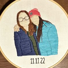 two people are standing together in front of a cross stitch embroidery hoop with the date 11 / 22 on it