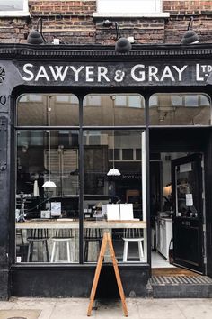 the storefront of sawer and gray is black with white lettering on it's windows