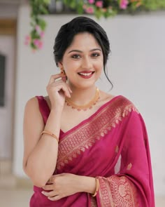 a woman in a pink sari is posing for the camera with her hand on her cheek