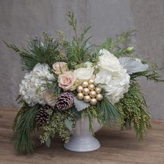 a white vase filled with flowers and greenery