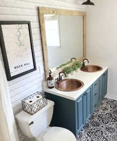 a white toilet sitting next to a bathroom sink under a wooden mirror mounted above it