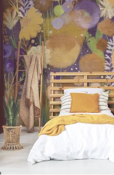 a bed sitting in front of a painting on the wall next to a basket filled with flowers