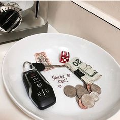 a white plate topped with lots of money and a car key sitting on top of it