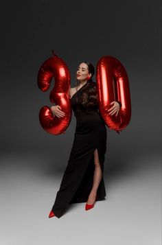 a woman in a black dress holding red balloons