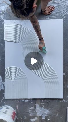 a woman is painting on the floor with white paint