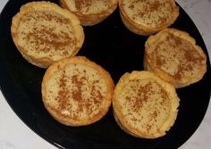 four small pastries sitting on top of a black plate