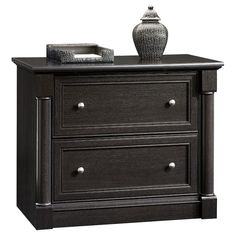 a black dresser with two drawers and a vase on top