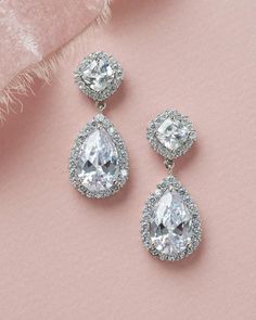 The epitome of classic bridal beauty, our Allure CZ Wedding Earrings are designed with CZs surrounded by a halo of delicate stones that sparkle & shine like real diamonds. Perfect for brides & bridesmaids. Available in silver, these earrings are surprisingly lightweight for easy day to night wear. Cubic Zirconia Bridal Earrings With Halo Design For Wedding, Wedding Drop Diamond Earrings With Halo Design, Wedding Halo Drop Diamond Earrings, Wedding Halo Design Drop Diamond Earrings, Dazzling Halo Design Bridal Earrings For Party, Silver Halo Cubic Zirconia Diamond Earrings, Silver Cubic Zirconia Diamond Earrings With Halo, Pear-shaped Diamond Bridal Earrings With Sparkling Stones, Wedding Dangle Earrings With Halo Setting