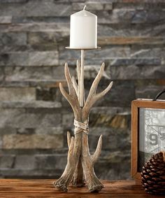 a white candle sitting on top of a wooden table next to a framed photo and pine cone