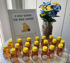 a table topped with lots of bottles of honey next to a vase filled with flowers