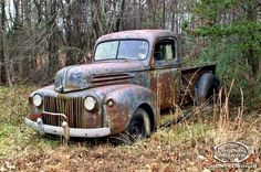 an old rusty truck sitting in the woods