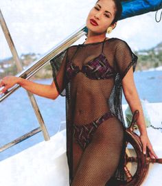 a woman sitting on the back of a boat wearing a fishnet bodystocker