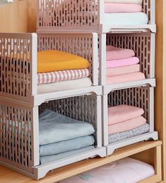 an organized closet with folded towels and folded clothes on shelves in front of a wooden wall