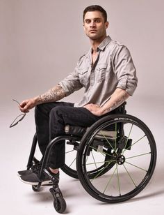 a man in a wheel chair with tattoos on his arm and leg, sitting down