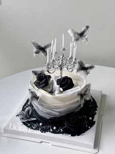 a cake decorated with black roses and candles