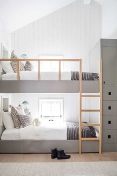 two bunk beds in a room with white walls and wood floors, one has a pair of black shoes on the floor