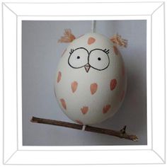 an egg with eyes painted on it sitting on a branch