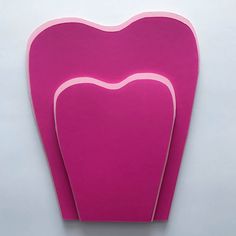 two pink heart shaped cutting boards sitting on top of a white table next to each other