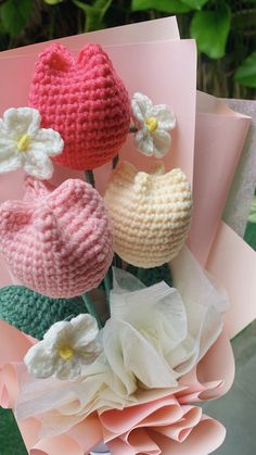 three crocheted flowers sitting on top of each other next to a pink card