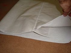 someone is folding the fabric on top of an unrolled piece of white paper