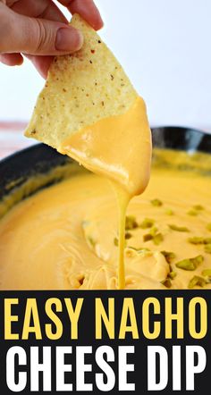 a hand dipping cheese into a black bowl filled with cheesy nachos