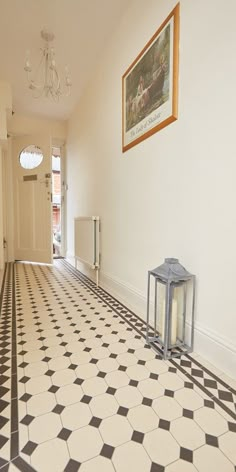 a hallway with a black and white checkered tile floor, chandelier and door