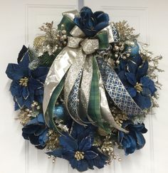 a wreath with blue and silver ribbons hanging on a door