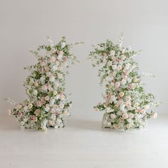 two vases with flowers on them sitting next to each other in front of a white wall