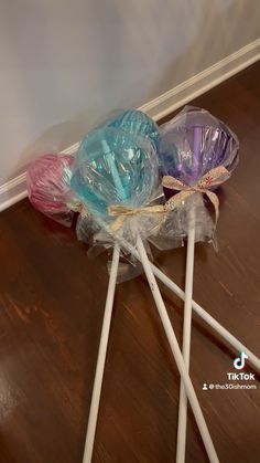 three lollipops wrapped in plastic sitting on the floor