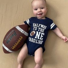 a baby laying on the ground with a football