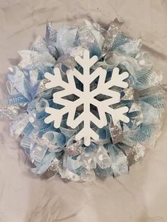 a snowflake wreath with ribbons and bows on a sheet of white paper in the shape of a snowflake