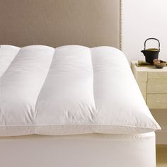 an unmade bed with white pillows and a brown headboard on the side table