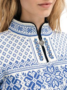 a woman wearing a blue and white sweater with an embroidered design on the collarline