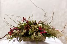 a vase filled with flowers and greenery sitting on top of a white table cloth