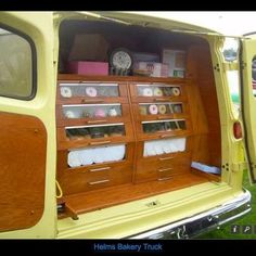 the back end of an old yellow truck with its doors open and shelves full of donuts